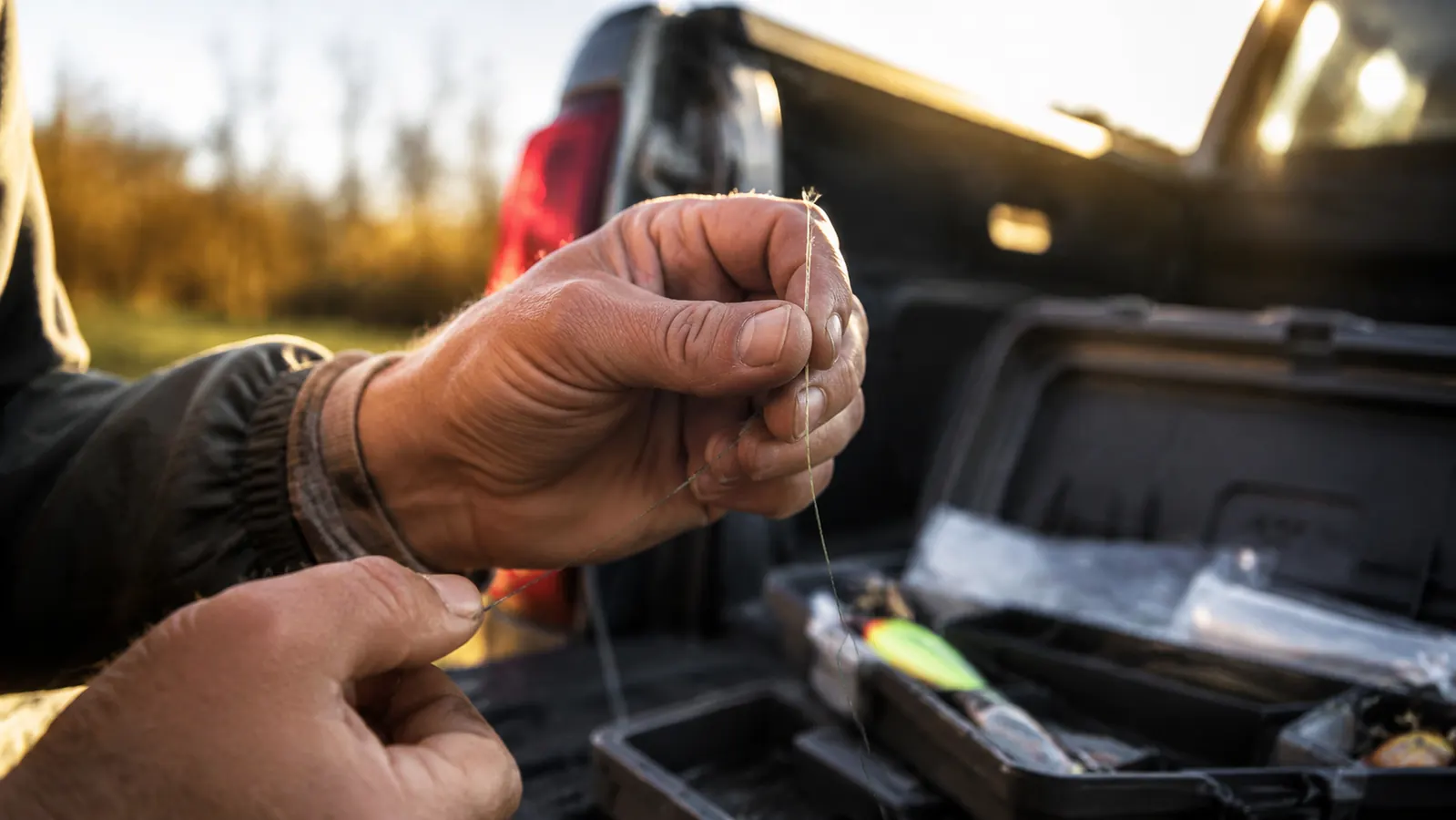 A fisherman's hands holding the end of braided line up to the light to check for frayed spots